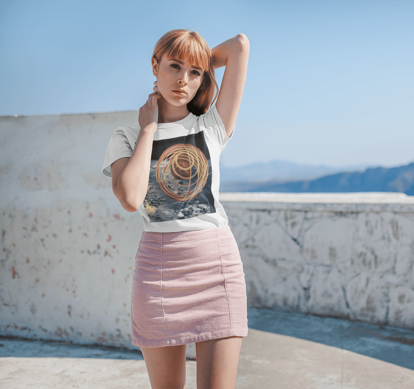 Mujer frente al mar con camiseta blanca y diseño fotográfico rectangular Orbit.